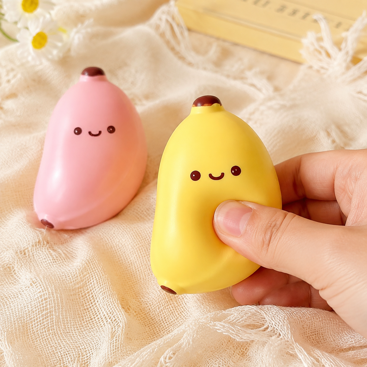 Hand pressing the yellow banana sensory toy with pink option shown