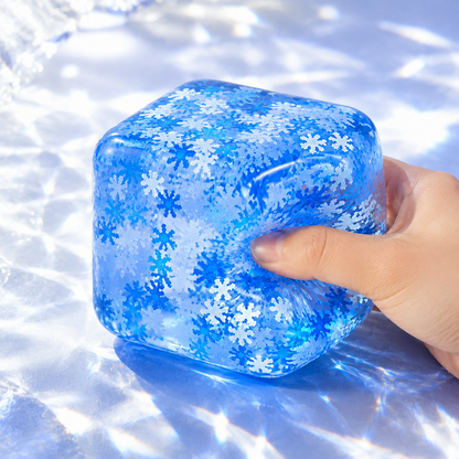 Blue snowflake rounded cube sensory squeeze toy with a hand pressing the same toy