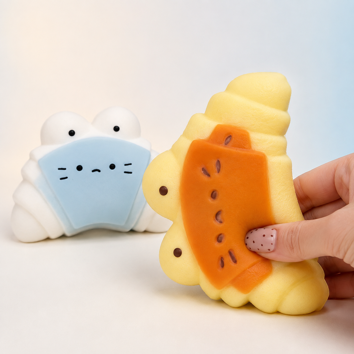Hand pressing caramel cheese croissant toy beside sea salt variant