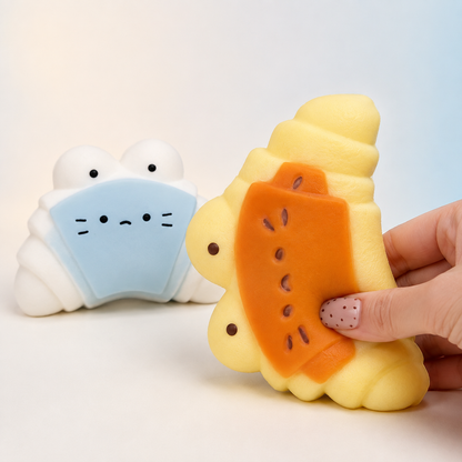 Hand pressing caramel cheese croissant toy beside sea salt variant