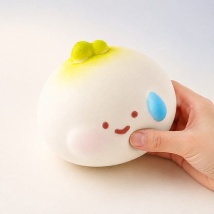 Onion slow-rise squishy with a hand gently squeezing the lower-right side