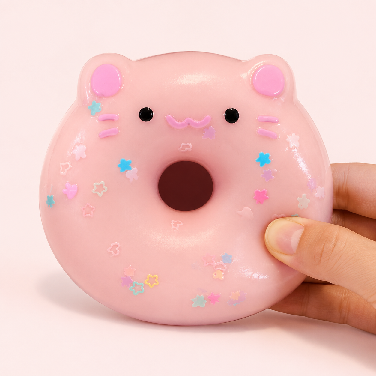 Hand pressing a pale pink pig donut sensory squeeze toy
