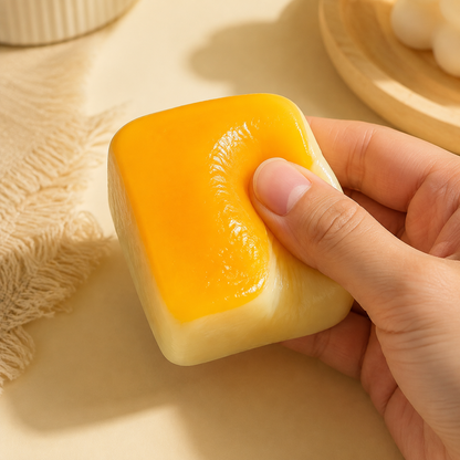 Hand pressing a golden stretchy rice-cake sensory toy