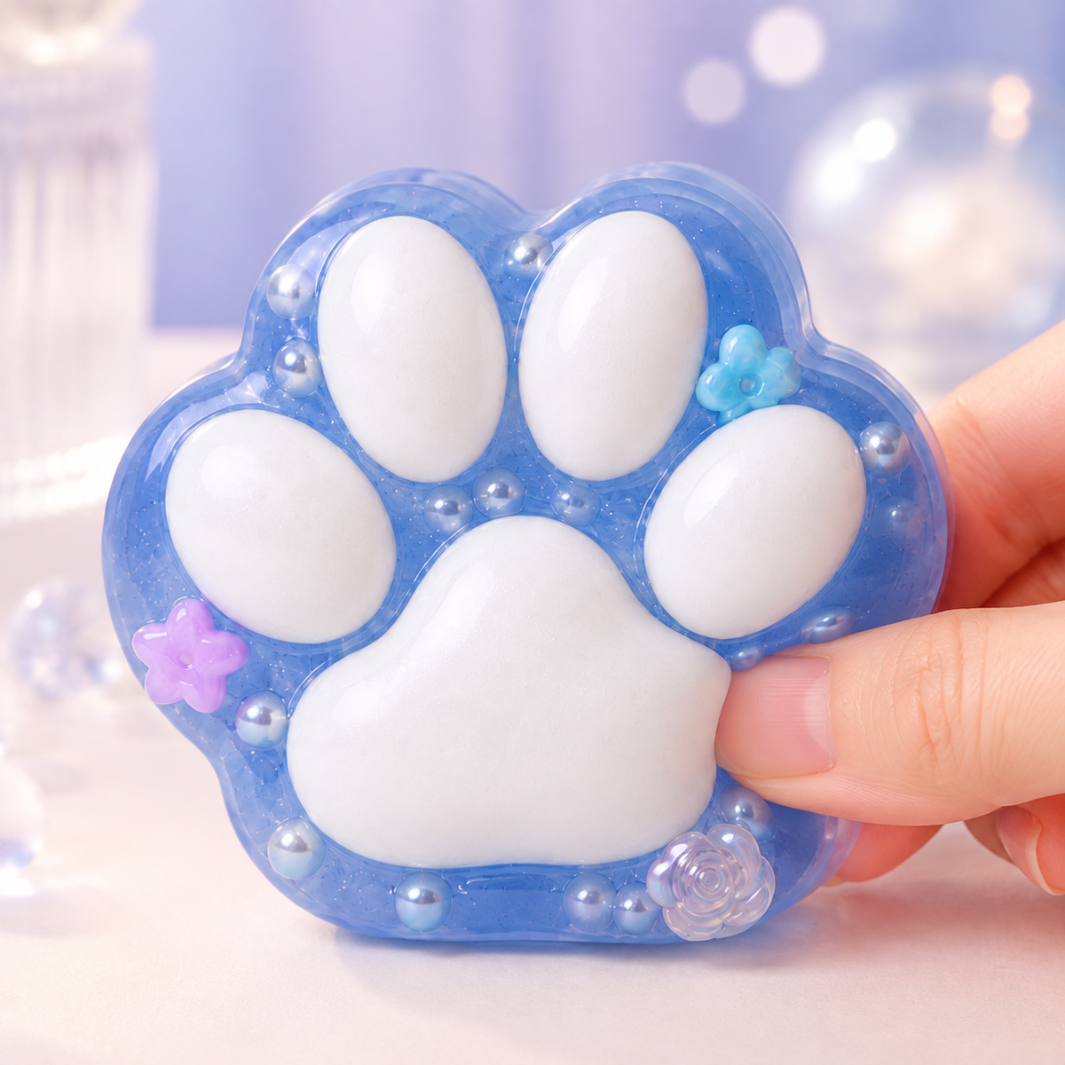 Translucent blue cat-paw sensory squeeze toy with a hand pressing the same toy
