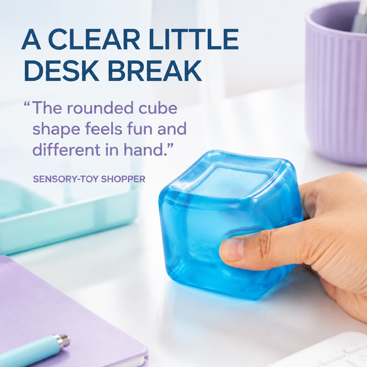 Transparent blue rounded cube sensory squeeze toy in a clean desk lifestyle scene