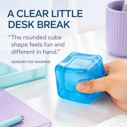 Transparent blue rounded cube sensory squeeze toy in a clean desk lifestyle scene