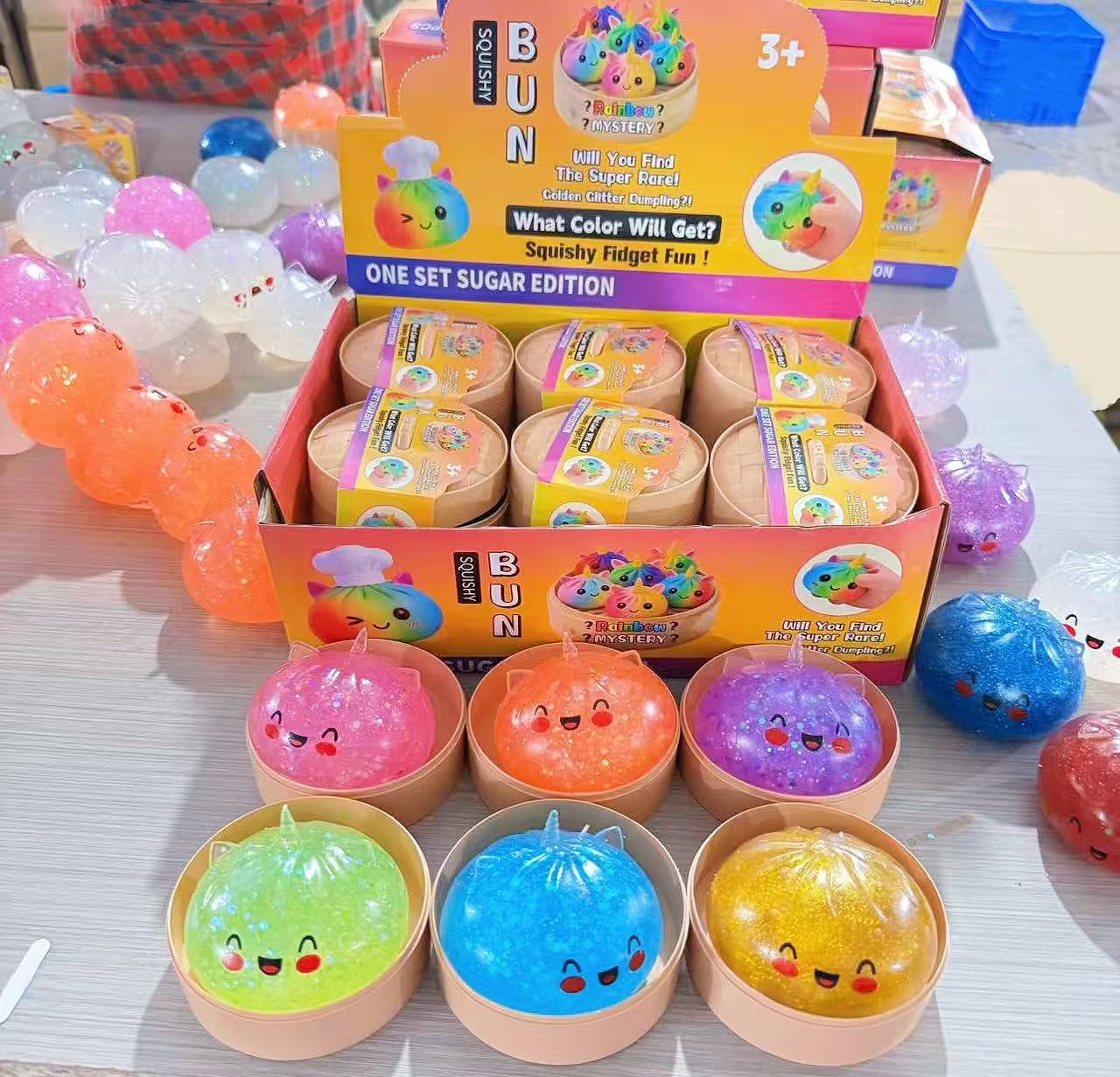 Assorted-colour glitter unicorn dumpling squishy toys in steamer-style containers; one toy per unit
